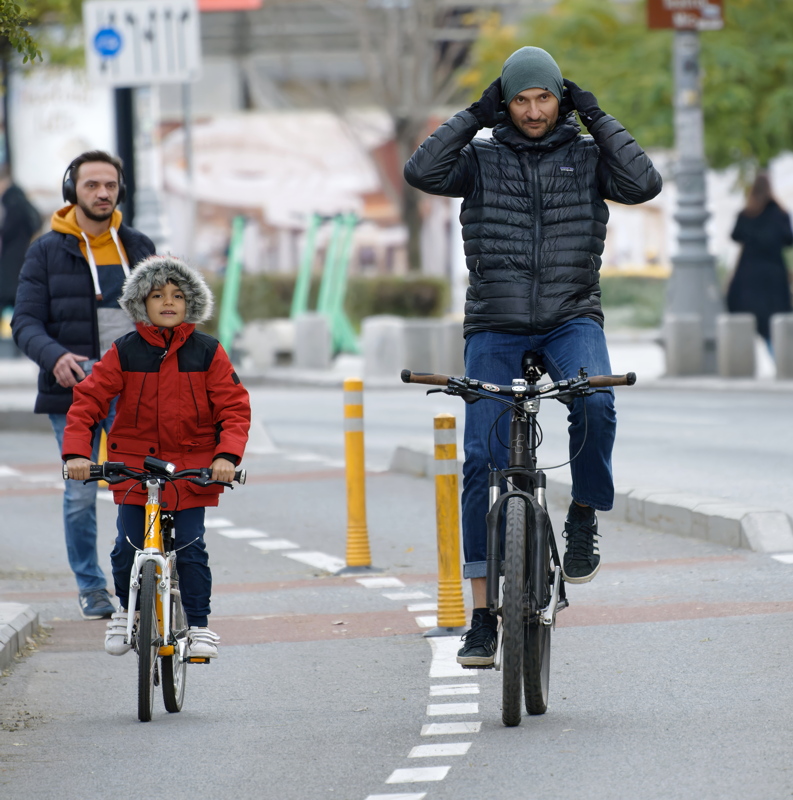 16 - Father and child riding bicycles together on a designated urban bike lane